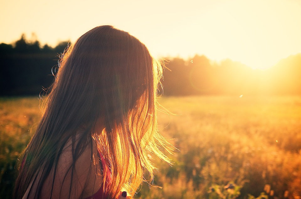 female with long hair looks at sunset 