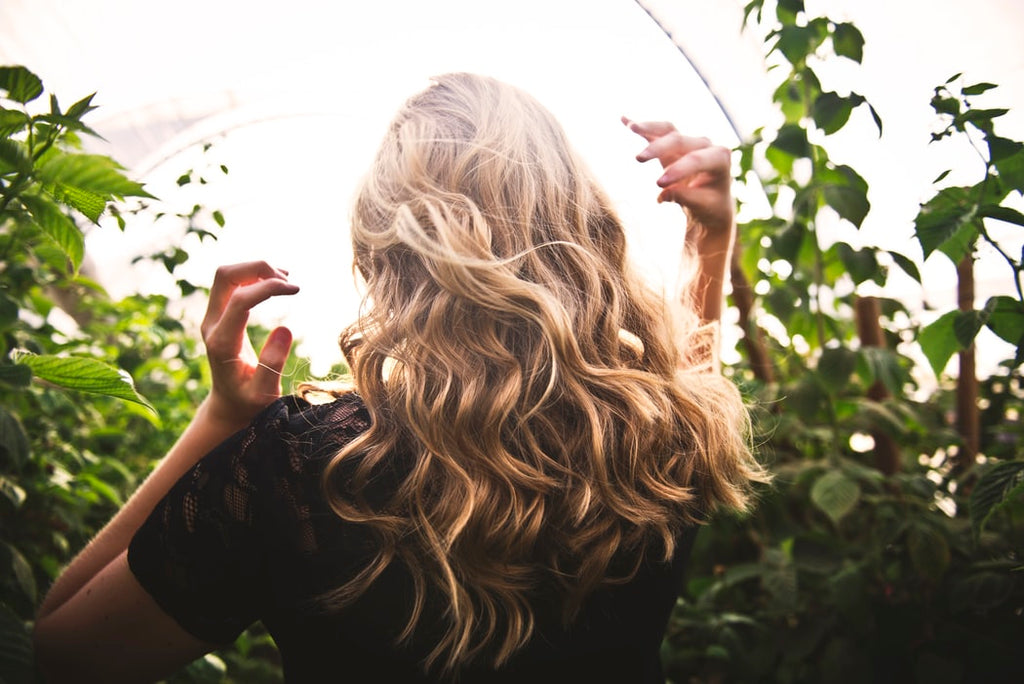 blonde woman with curled hair walking though vines